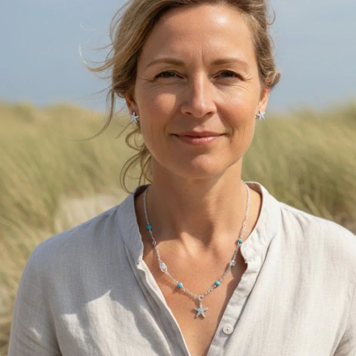 Frau mit maritimer Silberkette mit türkisfarbenen Perlen und Seestern-Anhänger am Strand