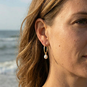 Damen-Ohr mit goldener Creole und weißem Perlenanhänger am Strand, maritimer Schmuck