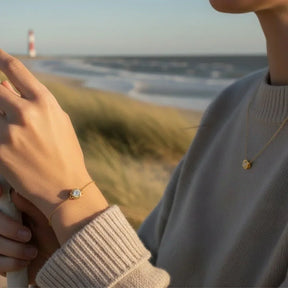 Goldener Anhänger Strahlender Knoten als Kette, maritimer Schmuck am Strand mit Leuchtturm