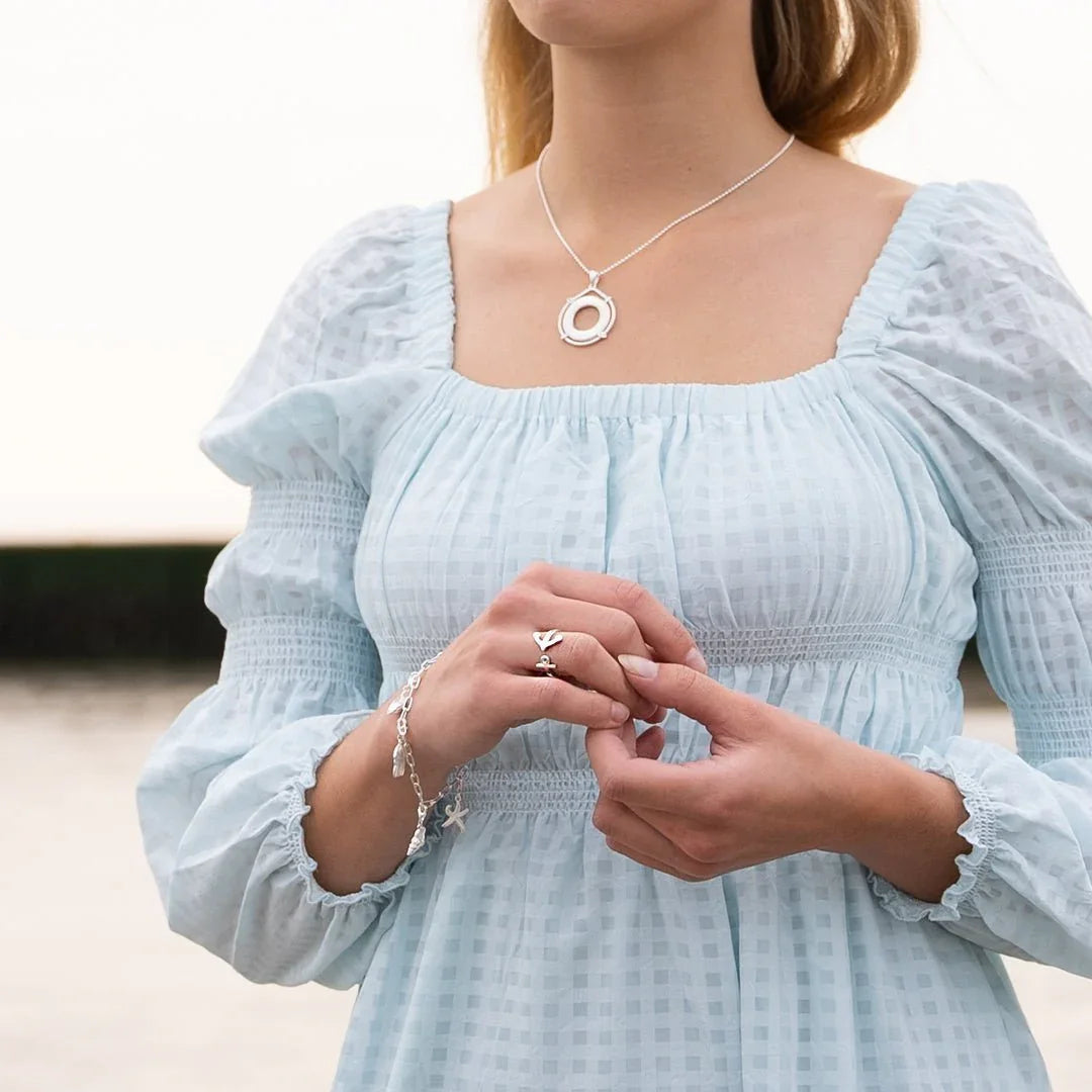 Frau trägt silbernen Ankerring, Armband und Kette im maritimen Stil am Strand