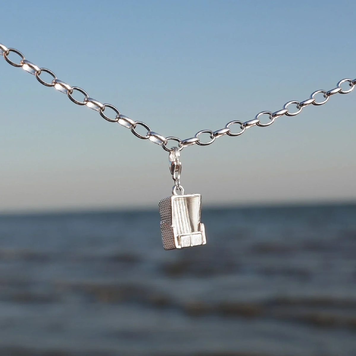 Silbernes Armband mit Strandkorb Charm vor Meer und blauem Himmel, maritimer Schmuck