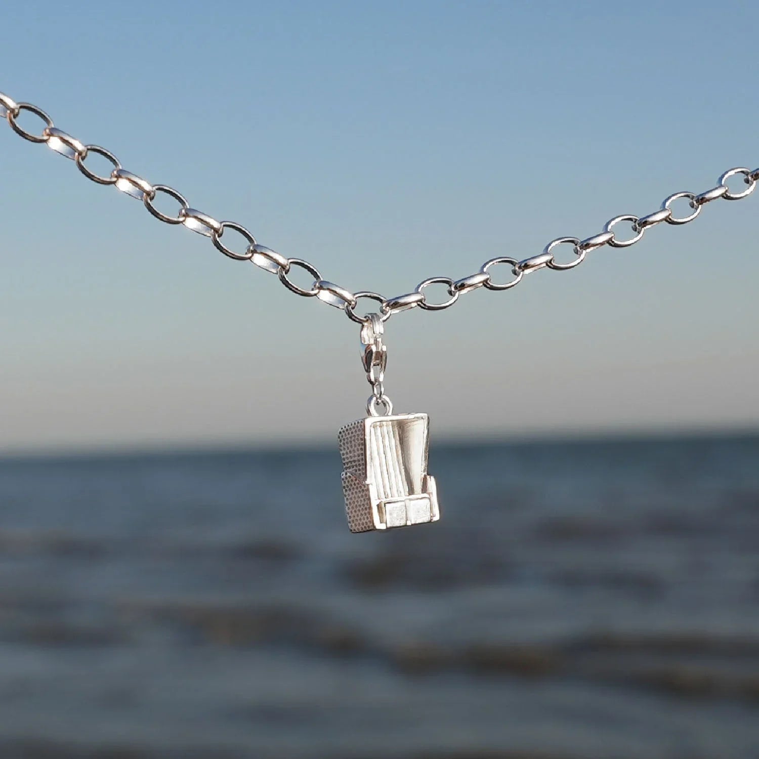 Silbernes Armband mit Strandkorb Charm vor Meer und blauem Himmel, maritimer Schmuck