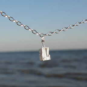 Silbernes Armband mit Strandkorb Charm vor Meer und blauem Himmel, maritimer Schmuck