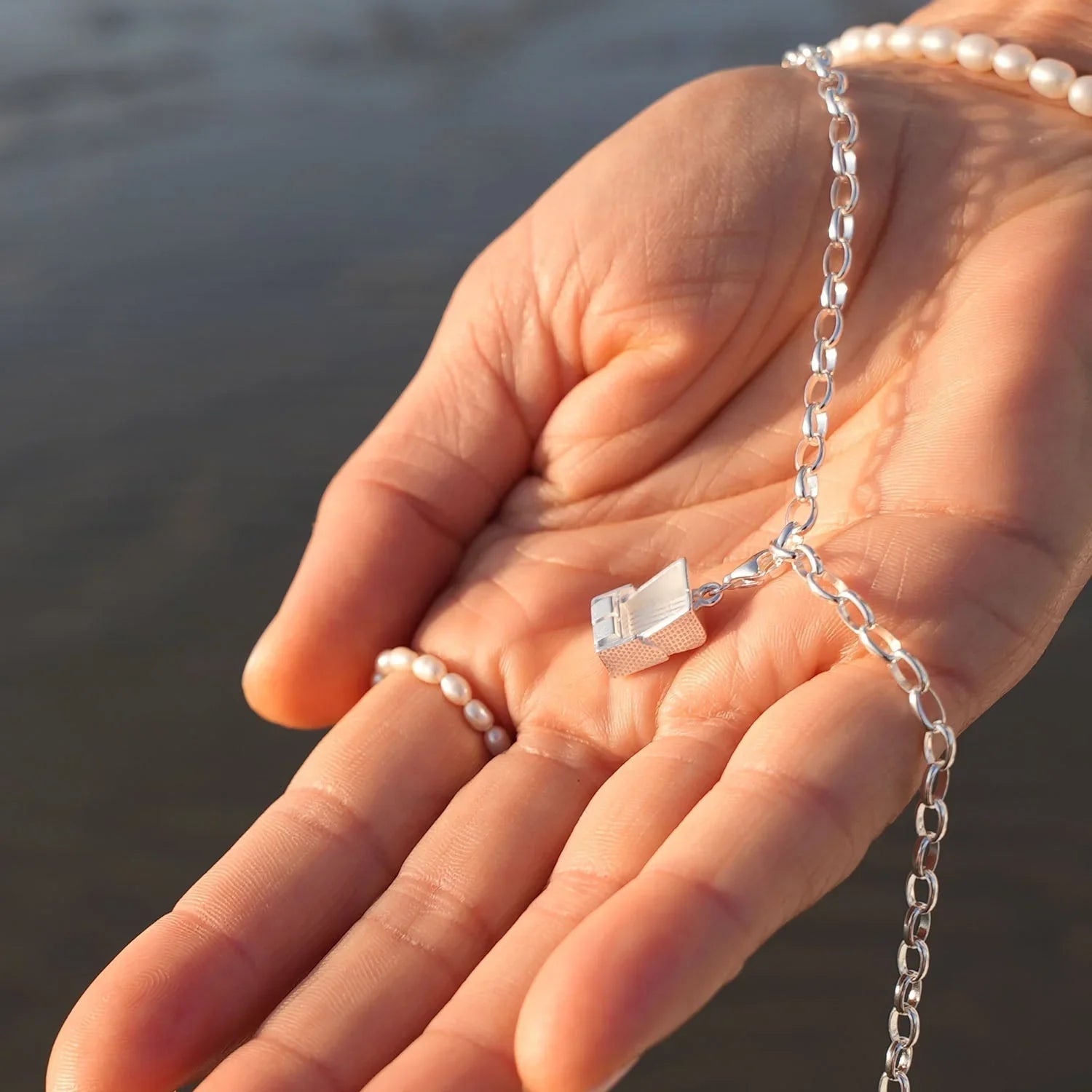 Silbernes Armband mit Strandkorb-Charm in Hand, maritimer Schmuck am Wasser