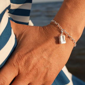 Silberarmband mit Strandkorb-Charm am Handgelenk vor maritimem Hintergrund
