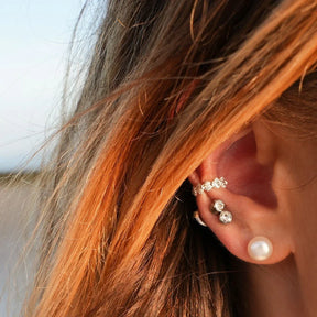 Silberner Ear Cuff in Muschelform am Ohr, kombiniert mit weiteren Ohrsteckern, maritimer Schmuck