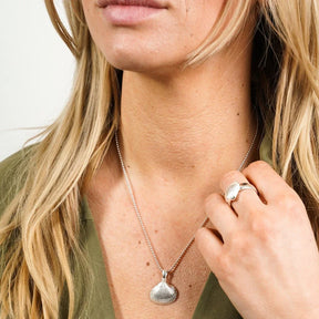 Frau mit silberner Herzmuschel-Kette und passendem Muschel-Ring, maritimer Schmuck