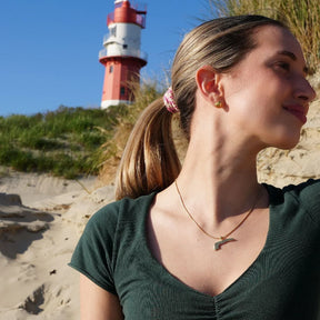 Frau mit goldener Kette am Strand vor Leuchtturm auf Langeoog, sonniger Sommertag