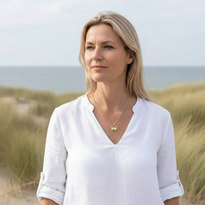 Frau am Strand mit goldener Kette mit Krebs-Anhänger, maritimer Schmuck, Naturkulisse