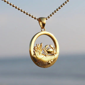 Goldene Kette mit rundem Anhänger, Krebs-Motiv, maritimer Schmuck vor Meereshintergrund