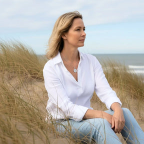 Frau am Strand mit rundem silbernen Meerjungfrau-Anhänger, maritimer Schmuck