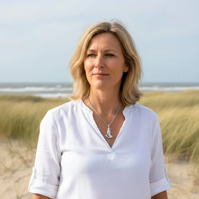Frau am Strand mit silberner Meerjungfrau-Kette, maritimer Schmuck, Dünen im Hintergrund