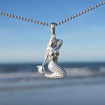 Silberner Meerjungfrau Anhänger an Kette vor Meeres-Hintergrund für maritimen Schmuck