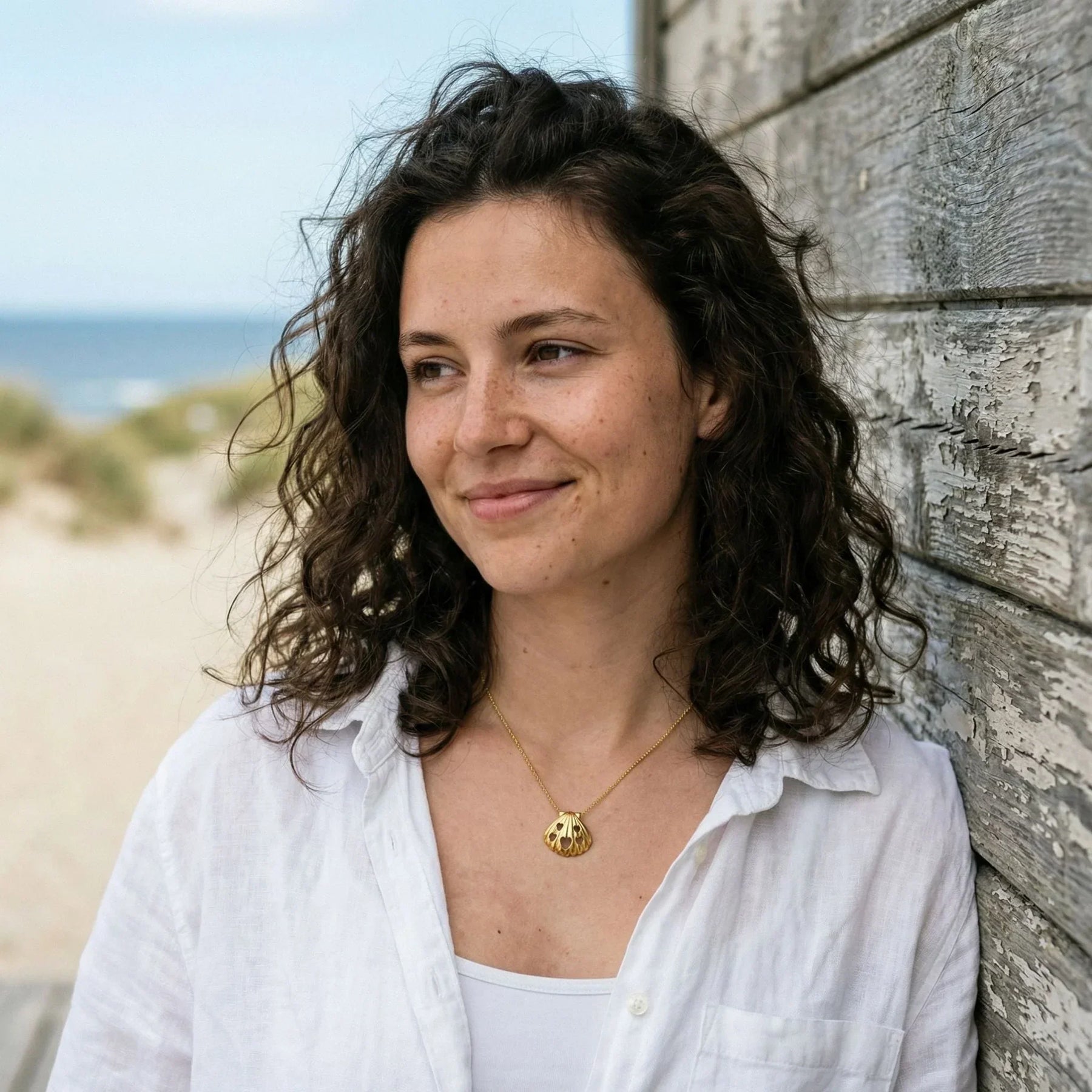 Frau am Strand mit goldener Muschel-Kette mit Herzanhängern, maritimer Schmuck