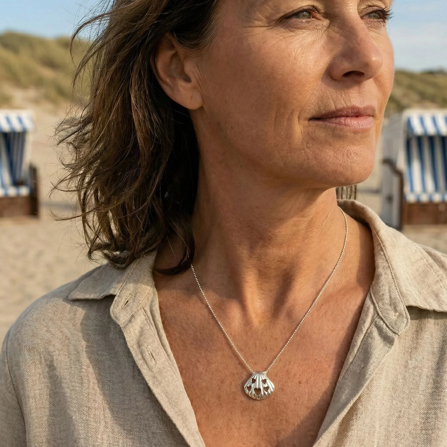 Frau am Strand mit silberner Muschel-Kette mit Herz-Details, maritimer Schmuck
