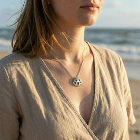 Frau mit Muschel-Anhänger aus Silber und Herzmotiven am Strand