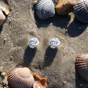Ohrstecker Knoten silber auf Sand mit Muscheln, maritimer Schmuck am Strand