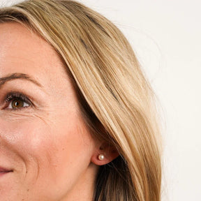 Frau mit elegantem Perlen Ohrstecker aus Gold am Ohr, Nahaufnahme, Schmuck Detail