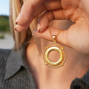Goldene Halskette mit maritimem Rettungsring-Anhänger und AHOI-Gravur am Hals einer Frau