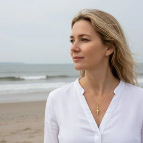 Frau am Strand mit goldener Ringelmuschel-Kette, maritimer Schmuck, Sommermode