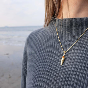 Goldene Muschel Halskette am Strand getragen, maritimer Schmuck mit Muschel-Anhänger.