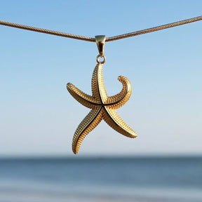 Goldene Seestern-Kette als maritimer Schmuck vor blauem Himmel und Meer