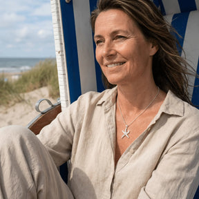 Frau am Strand trägt eine silberne Seestern-Kette, maritimer Schmuck, Sommer, Natur
