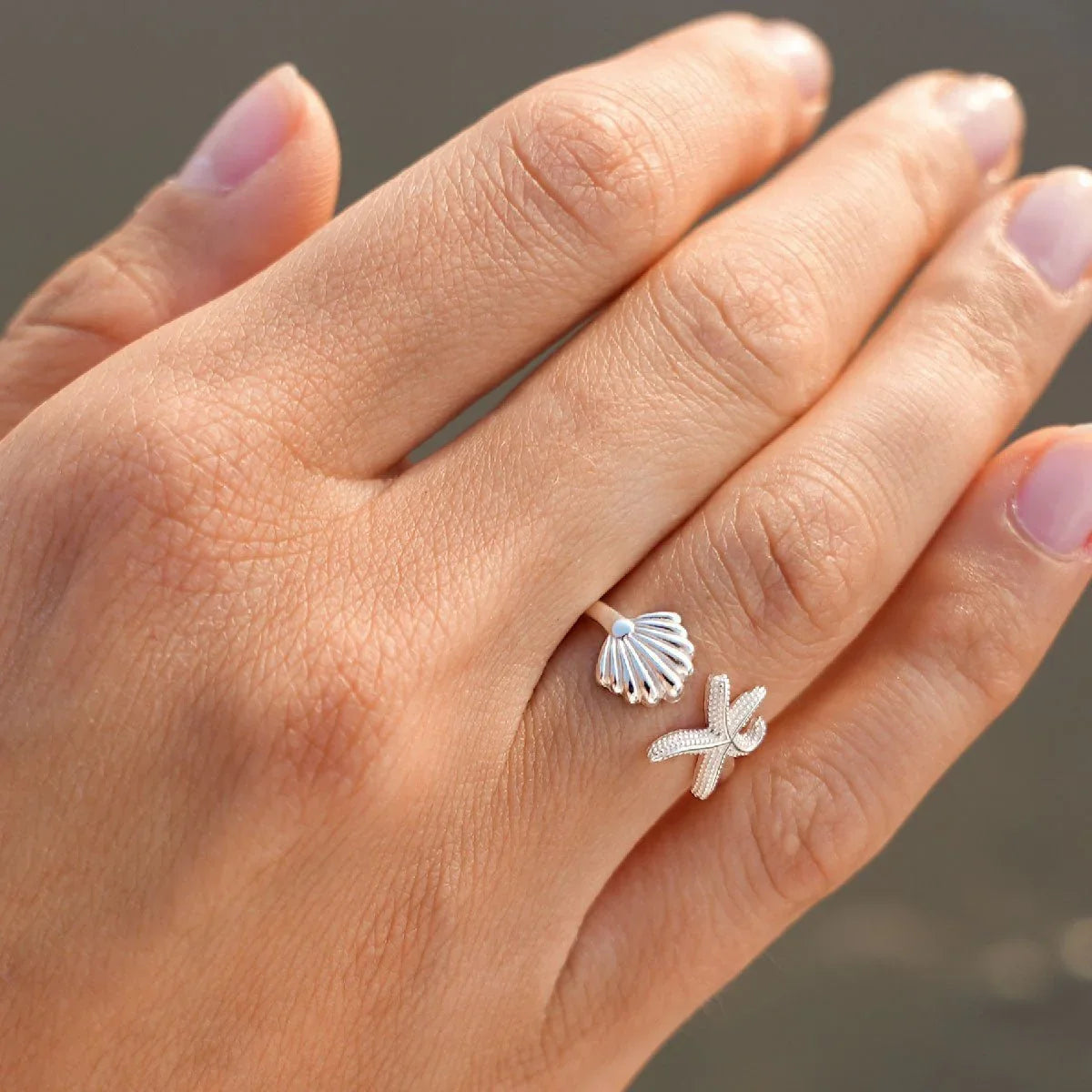 Silberner Seestern- und Muschelring im maritimen Design an einer Hand