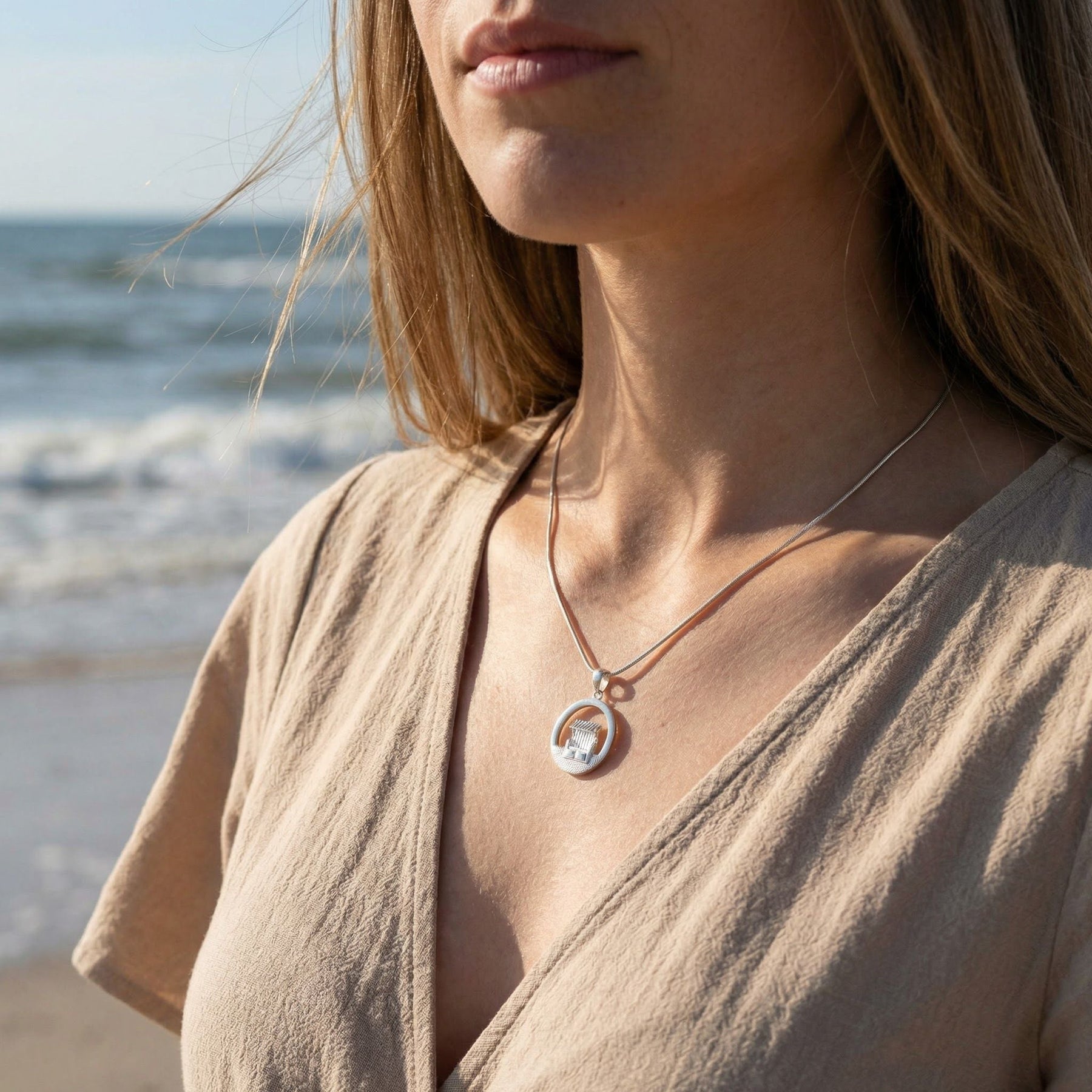 Frau am Strand trägt silberne Kette mit maritimem Strandkorb-Anhänger