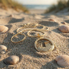 Goldene Kette mit Strandkorb-Anhänger im Sand, Muscheln, maritimer Schmuck am Strand