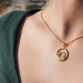 Goldene Kette mit rundem Anhänger, Motiv Strandkorb und Dünen, am Hals getragen