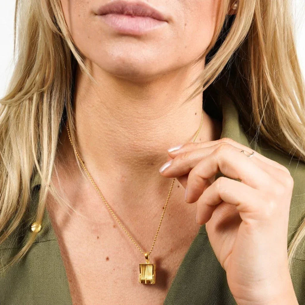 Frau trägt goldene Kette mit maritimem Anhänger, Nahaufnahme, moderner Schmuck