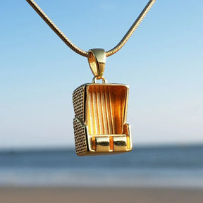 Goldener Strandkorb Anhänger maritimer Schmuck am Meer vor blauem Himmel