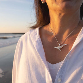 Frau mit silberner Wal-Kette am Strand bei Sonnenuntergang, maritimer Schmuck