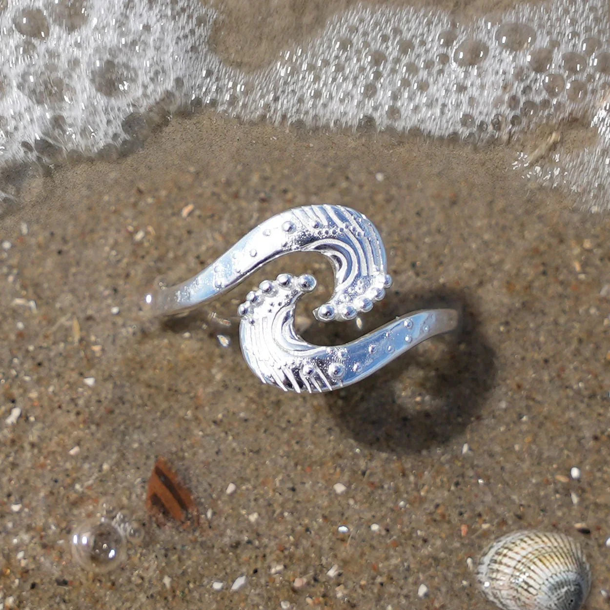 Silberner Wellenring im Sand am Strand, maritimer Schmuck mit Meeresmotiv