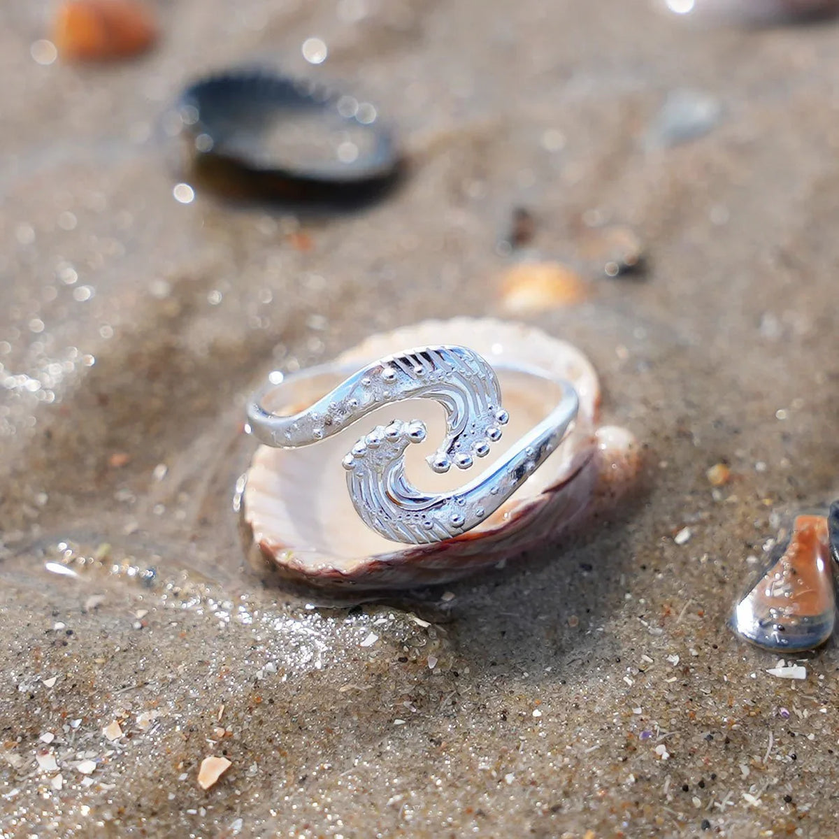 Silberner Wellenring maritim auf Muschel im Sand am Strand, Schmuck Meer