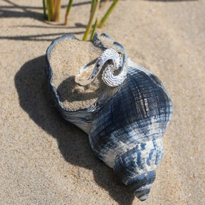 Silberner Wellenring auf Muschel im Sand, maritimer Schmuck am Strand